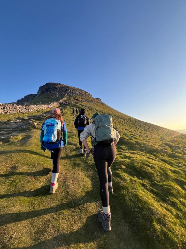 Three walkers climbing a hill