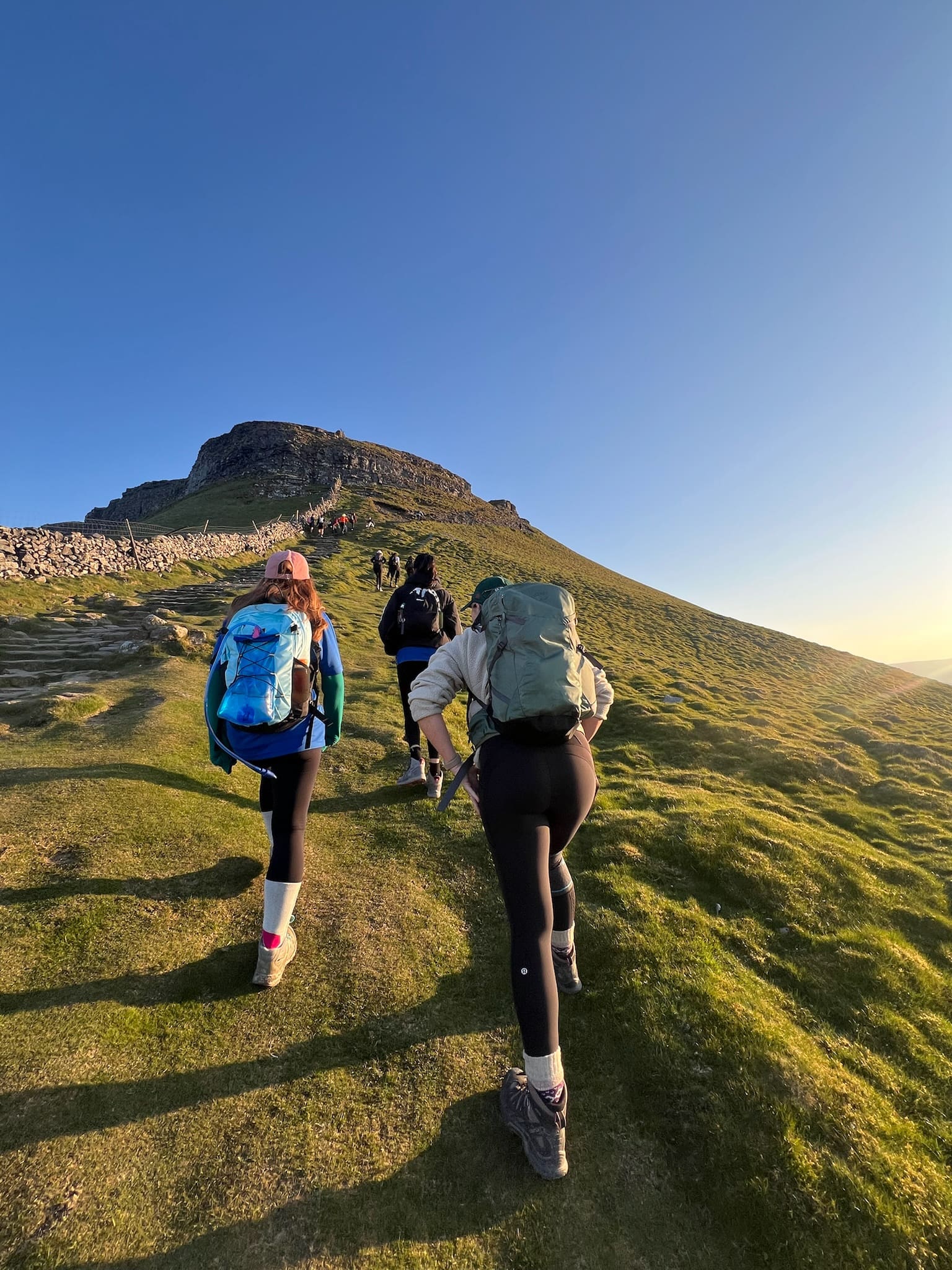 Three walkers climbing a hill