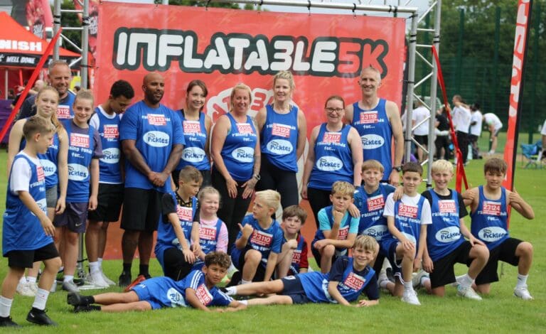 Image of a group of people wearing Ickle Pickle tops in front of an Inflatable sign.