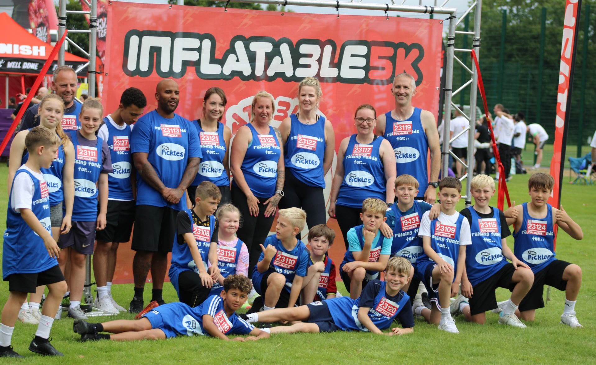 Image of a group of people wearing Ickle Pickle tops in front of an Inflatable sign.