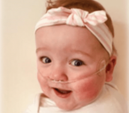 Baby Annabelle smiling wearing a pink hairband