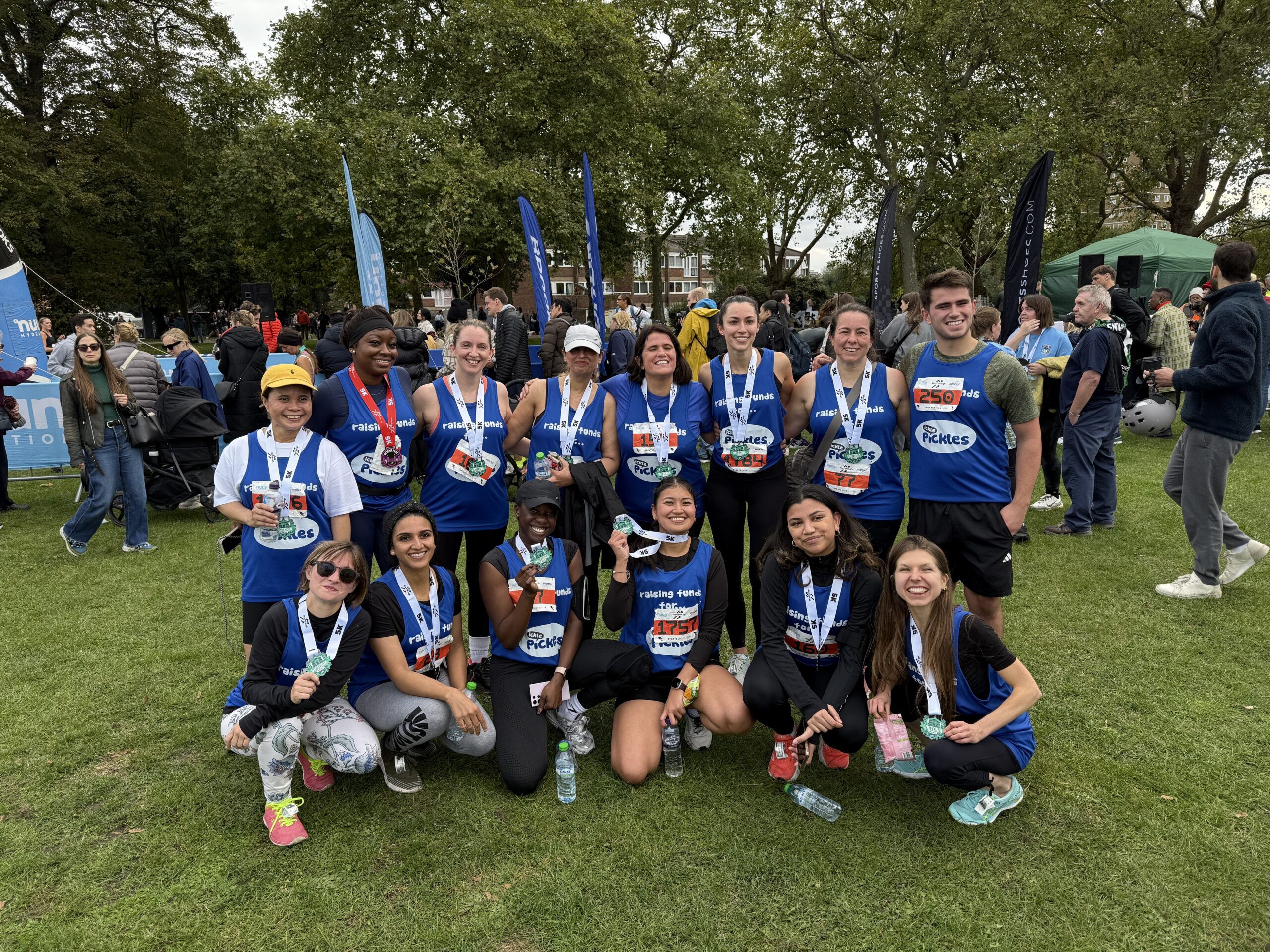 A group of runners wearing ickle pickle t-shirts wearing their race medals