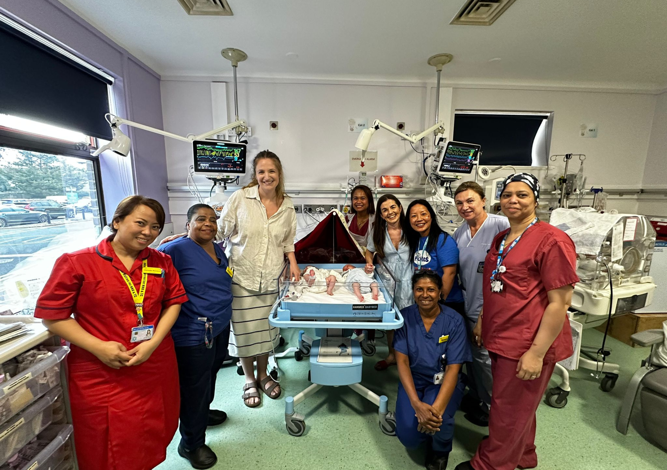 Neonatal staff with donated twin cot and a NICU family