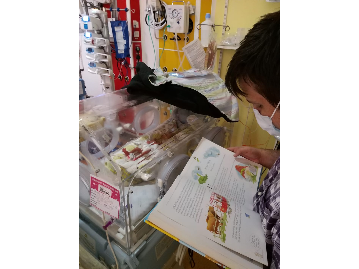 Nathan reading to Phoebe next to the incubator