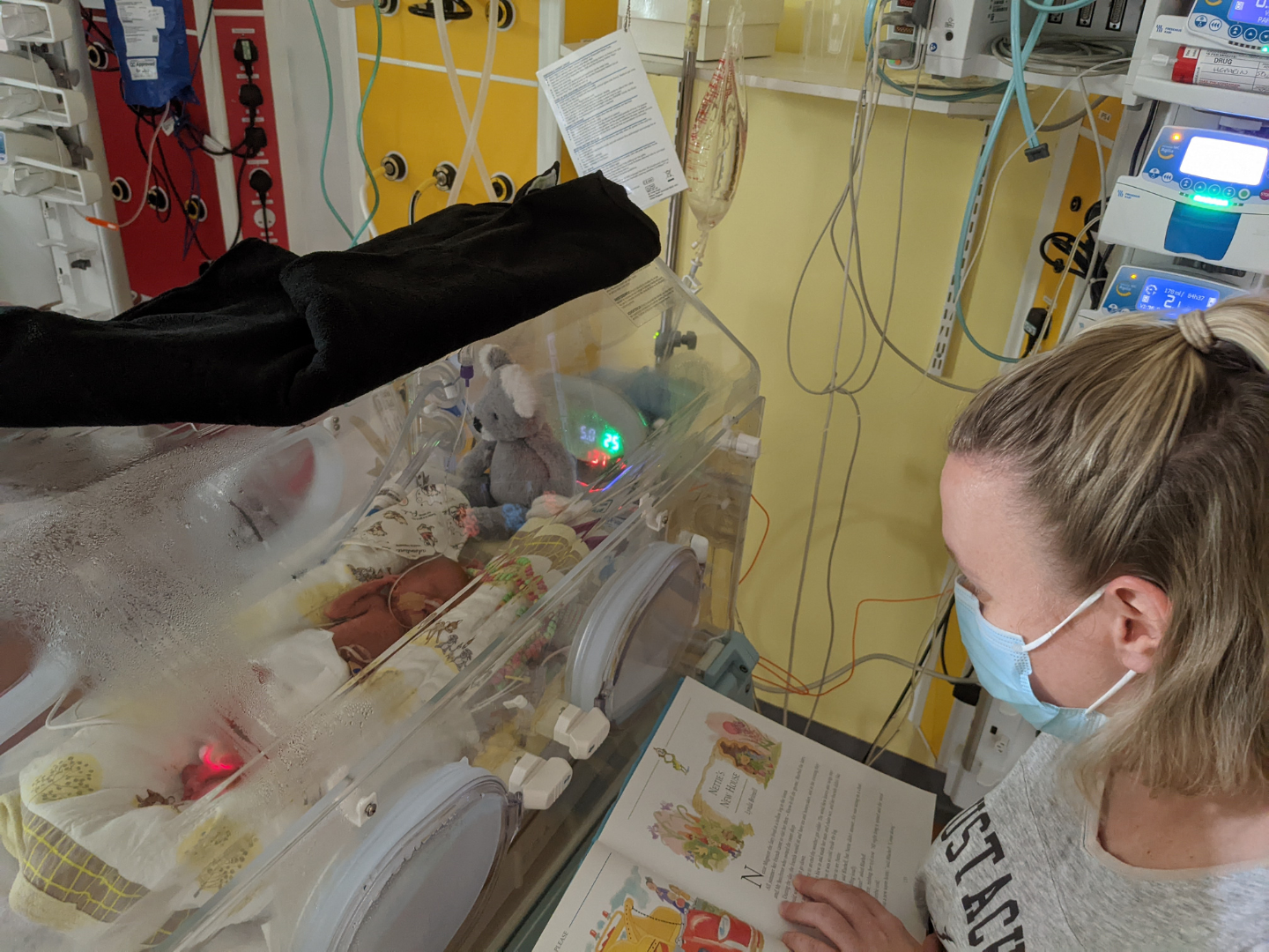 Lisa reading next to Phoebe in the incubator